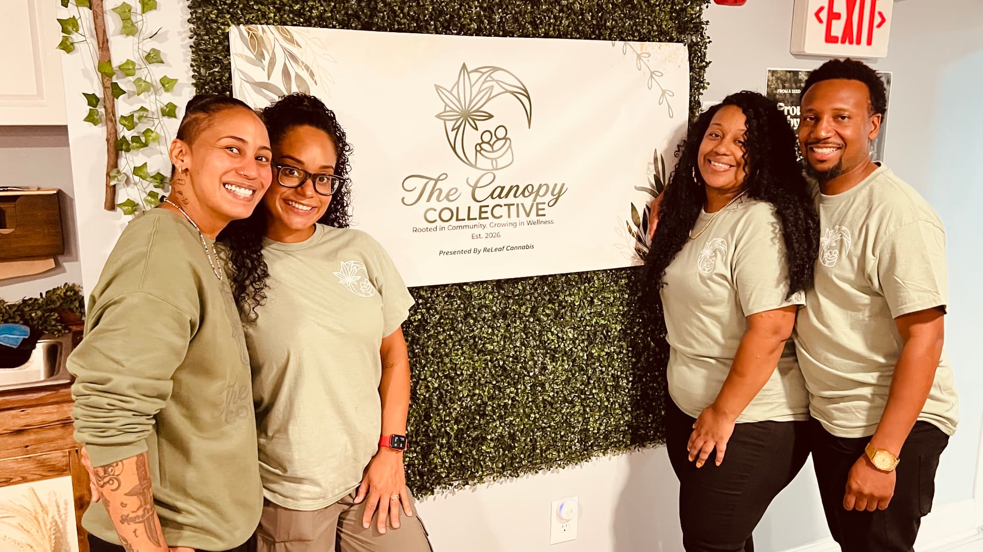 Four Canopy team members smiling in front of The Canopy Collective banner.